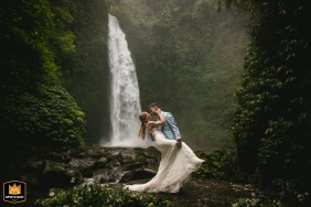 Bride and groom posing together by a waterfall in Bali, Indonesia.